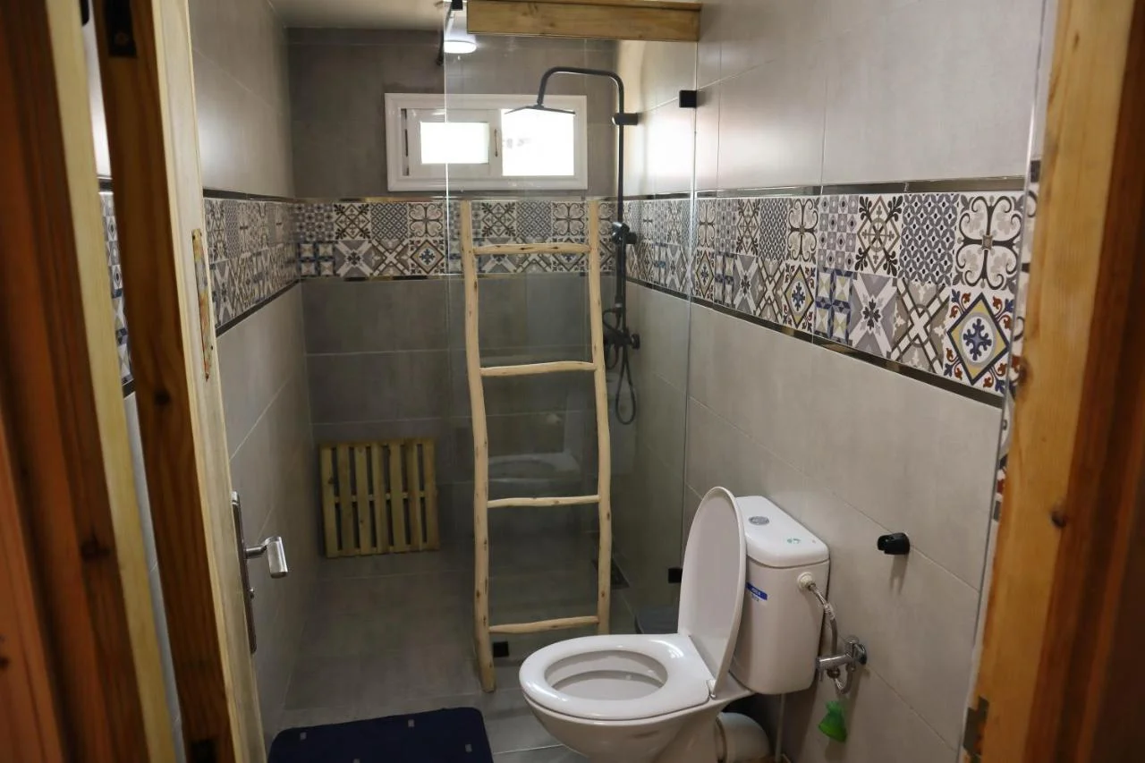 Shared bathroom at Grip Sea Morocco in Anza with patterned tile, a glass shower screen and toilet