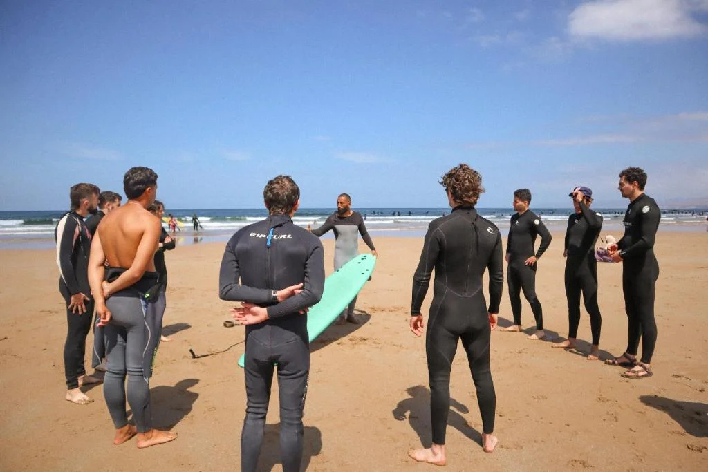Jamal speaking with a small circle of surf camp guests on the beach before their session