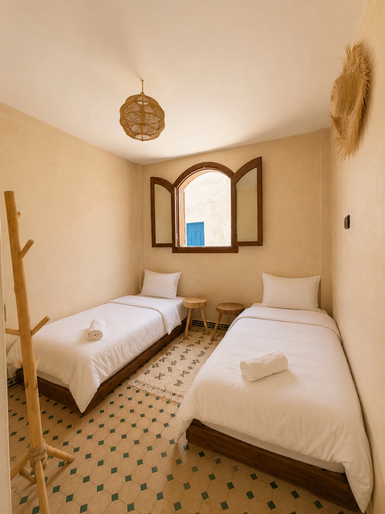 A room at the Kymata base in Tamraght: made-up double bed, timber headboard, wardrobe and tiled floor