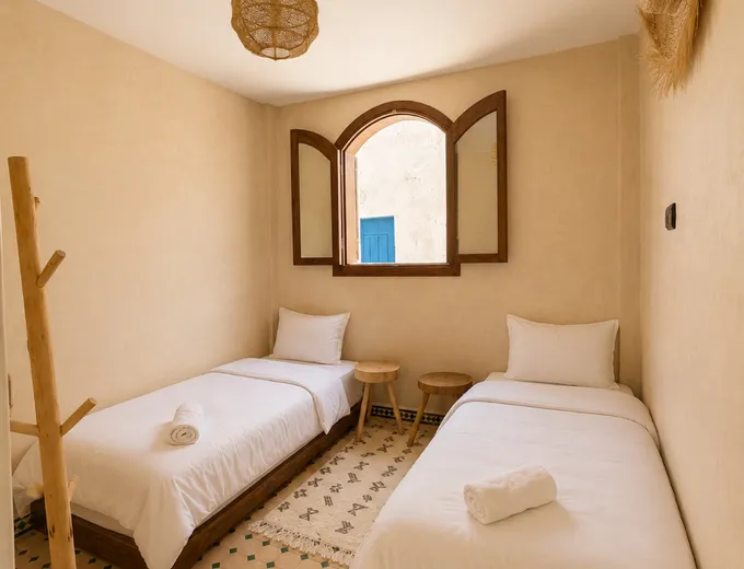 A room at the Kymata base in Tamraght: made-up double bed, timber headboard, wardrobe and tiled floor